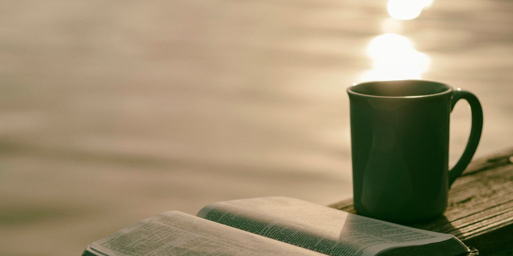 green ceramic mug beside book