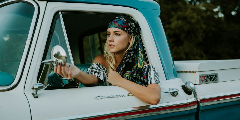 photography of woman holding side mirror in white and green 2-door pickup truck
